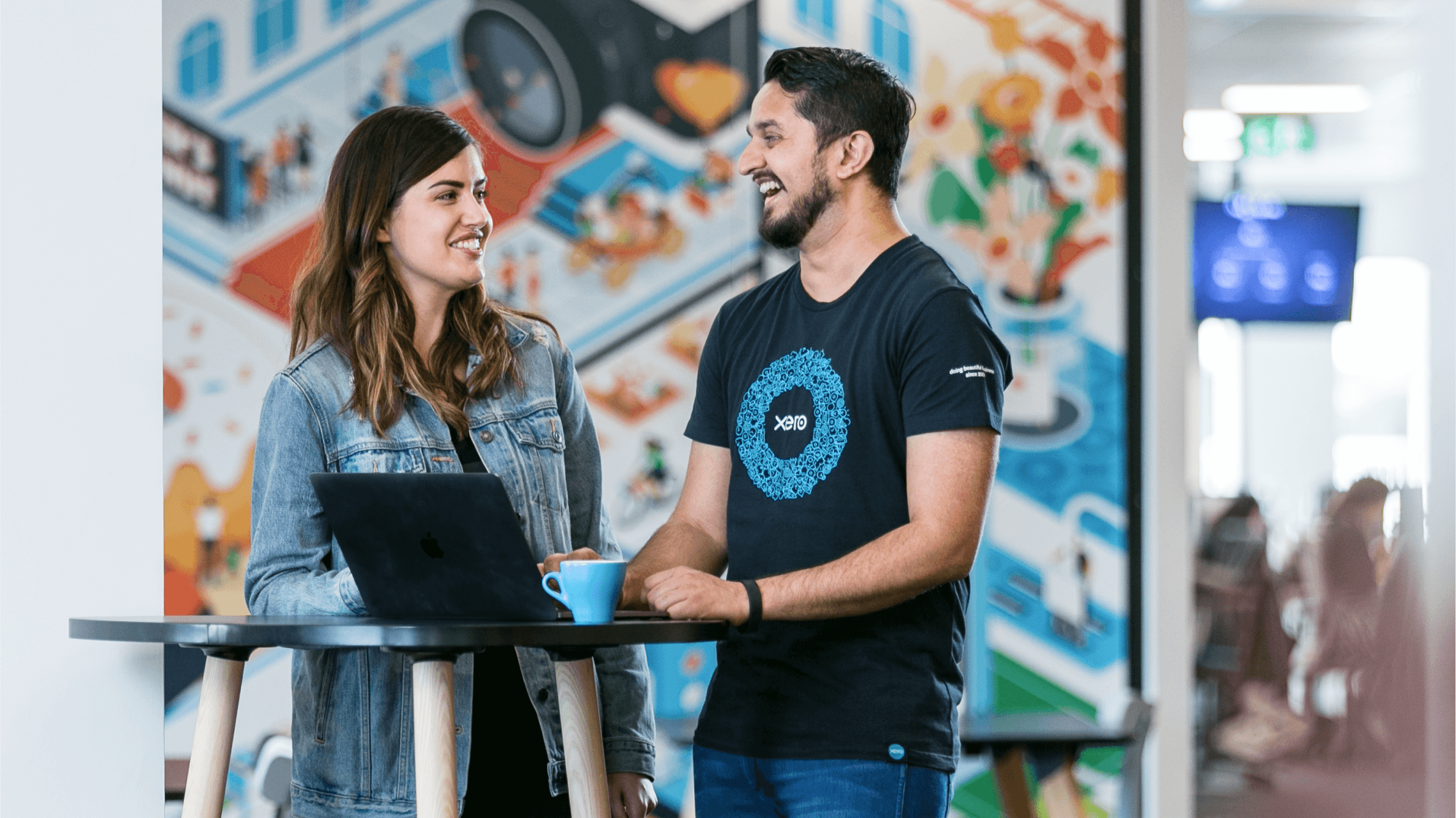 Two Xero employees discuss work over a coffee at one of Xero’s vibrant offices.