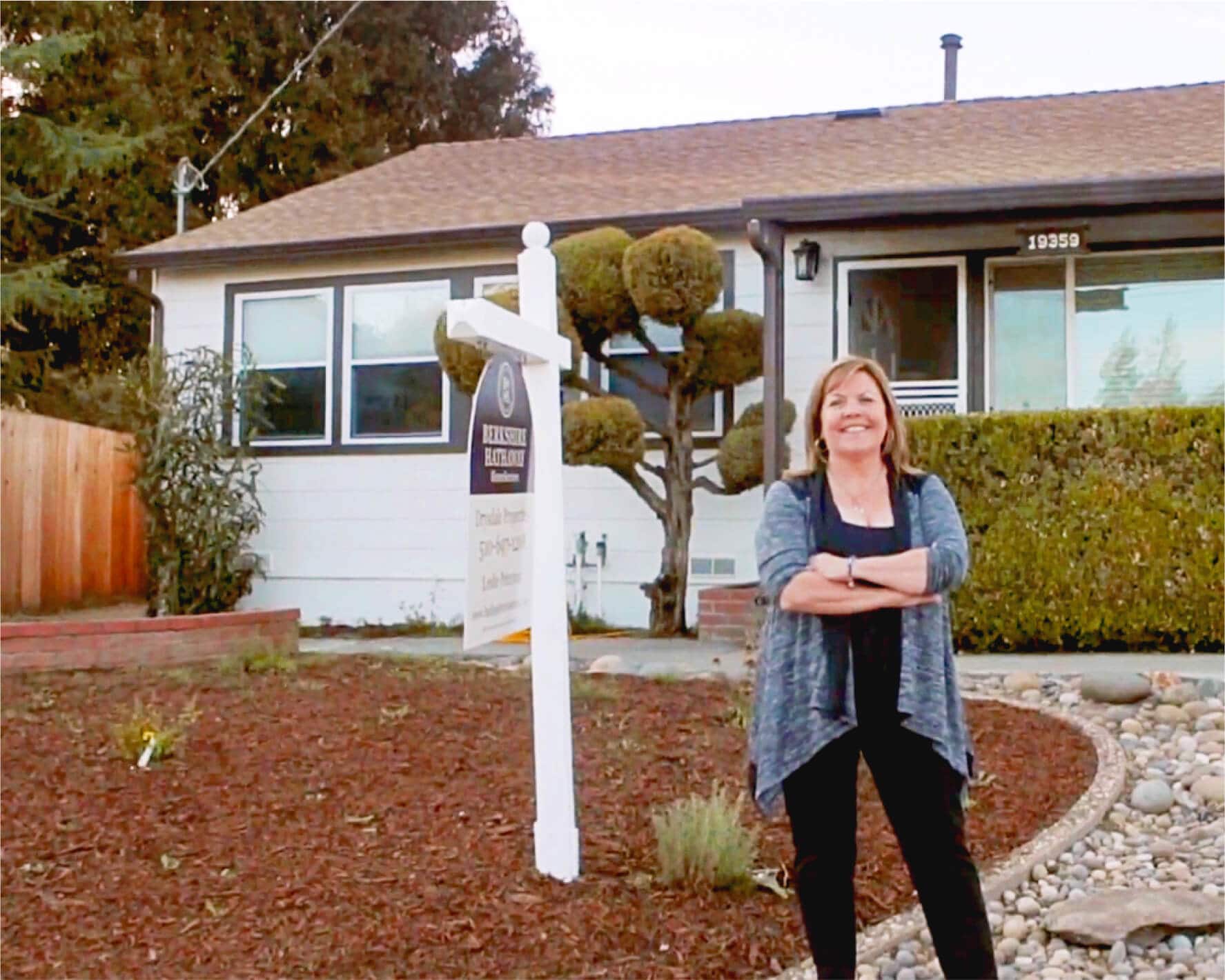 Real estate agent Leslie Peterson stands in front of a house-for-sale sign that she’s just put up.