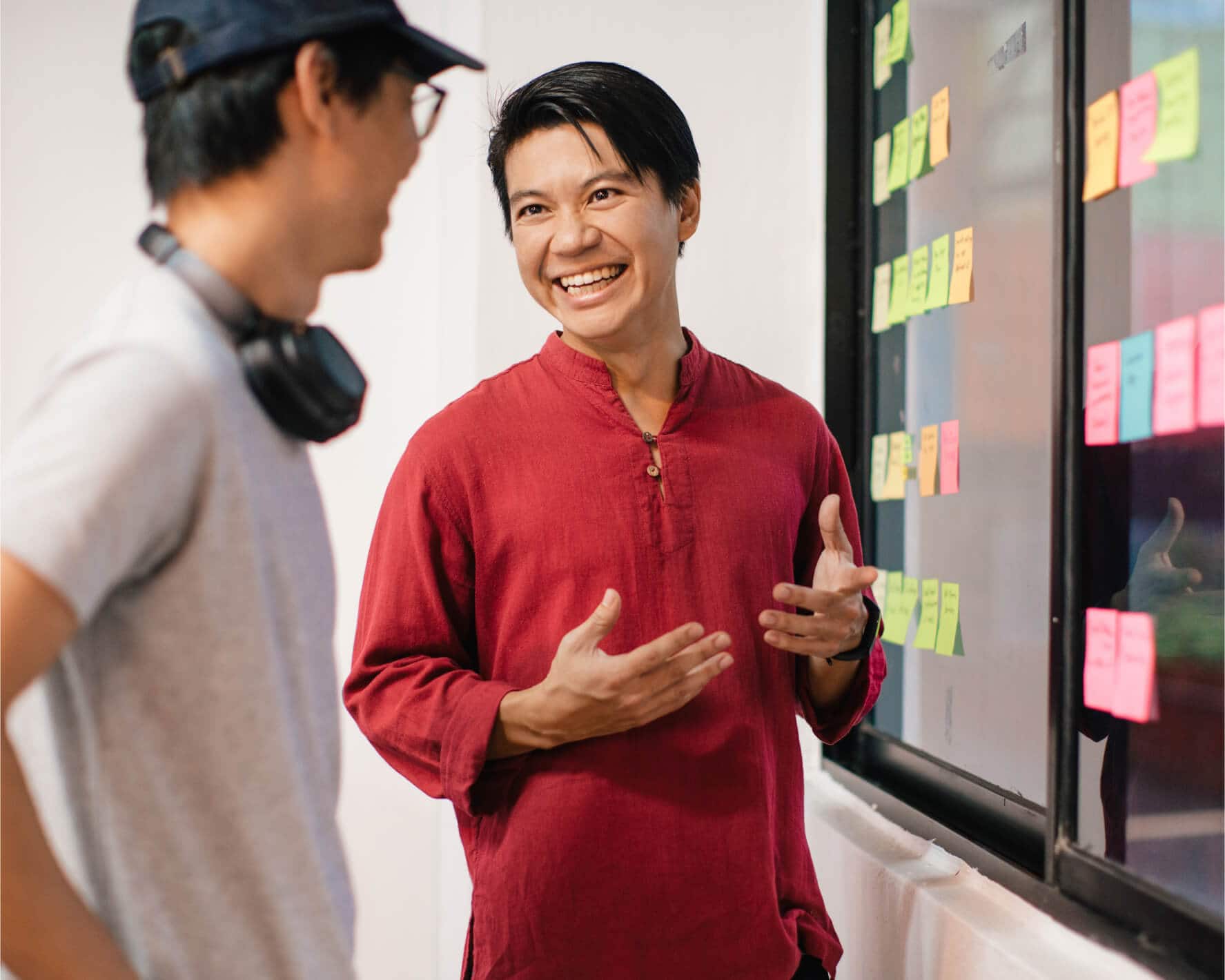 A startup founder and a team member discuss how to prioritize tasks that are listed on color-coded sticky notes.