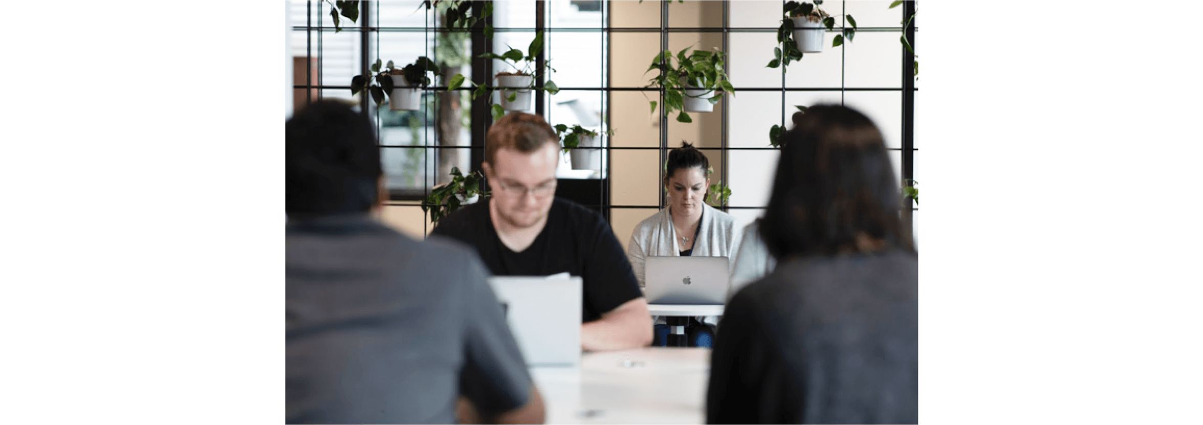 Four self-employed people work at tables in a light, bright co-working space.