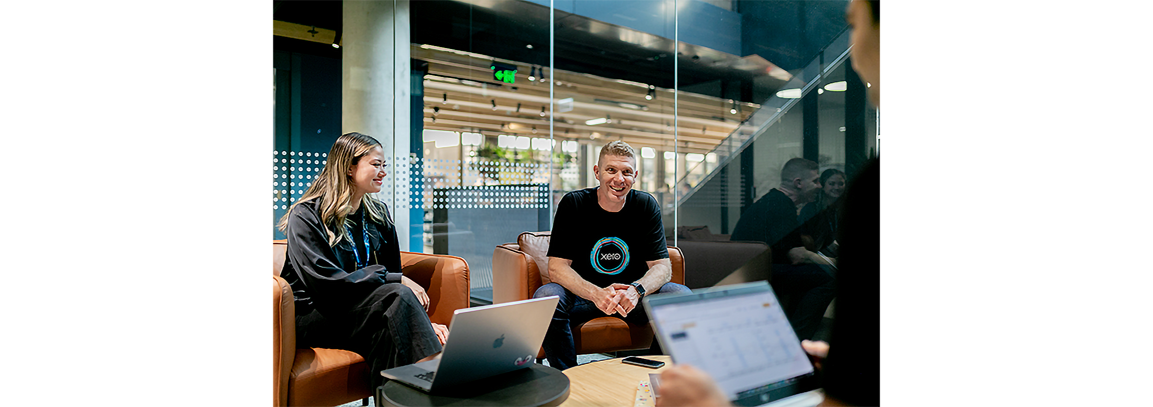 Three of the Xero team gather in comfortable chairs with their laptops,for a work meeting.