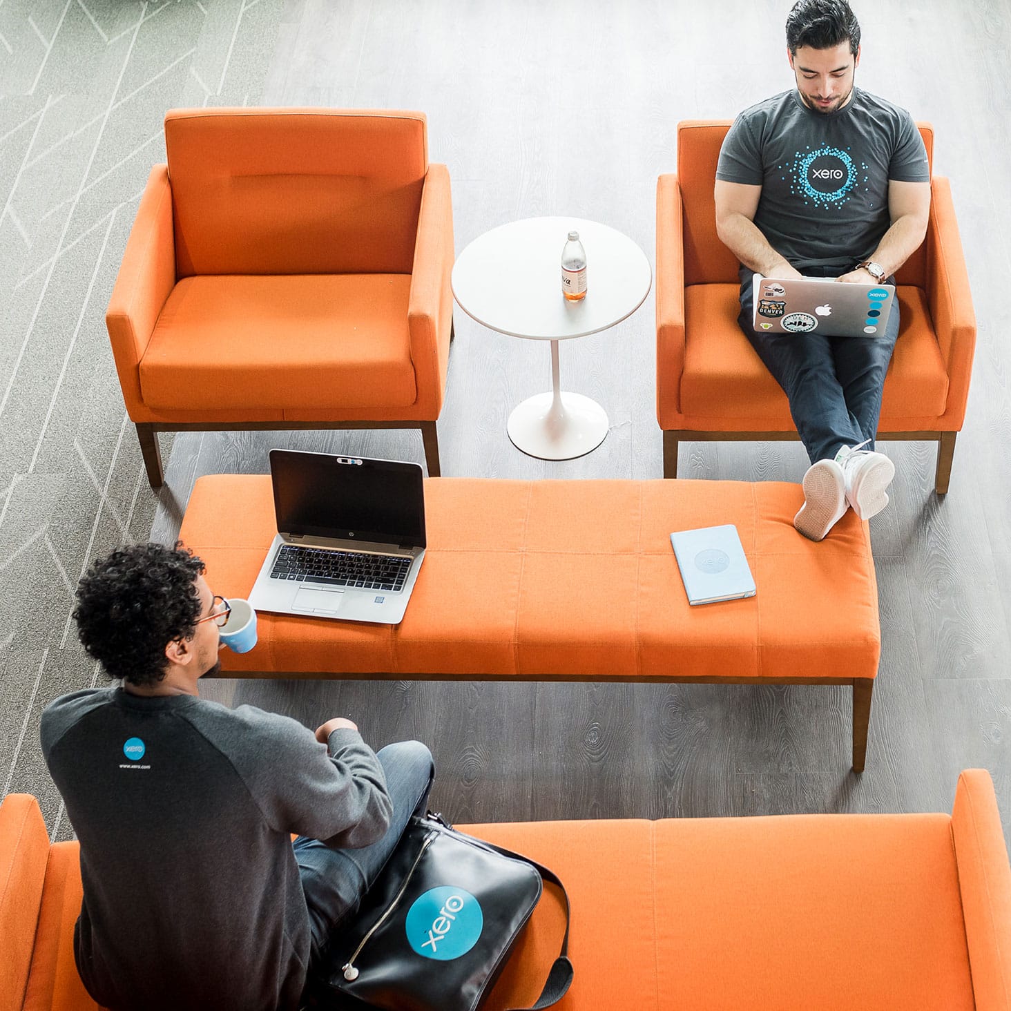Two Xeros sit across each other on orange couches and focus on doing beautiful work.