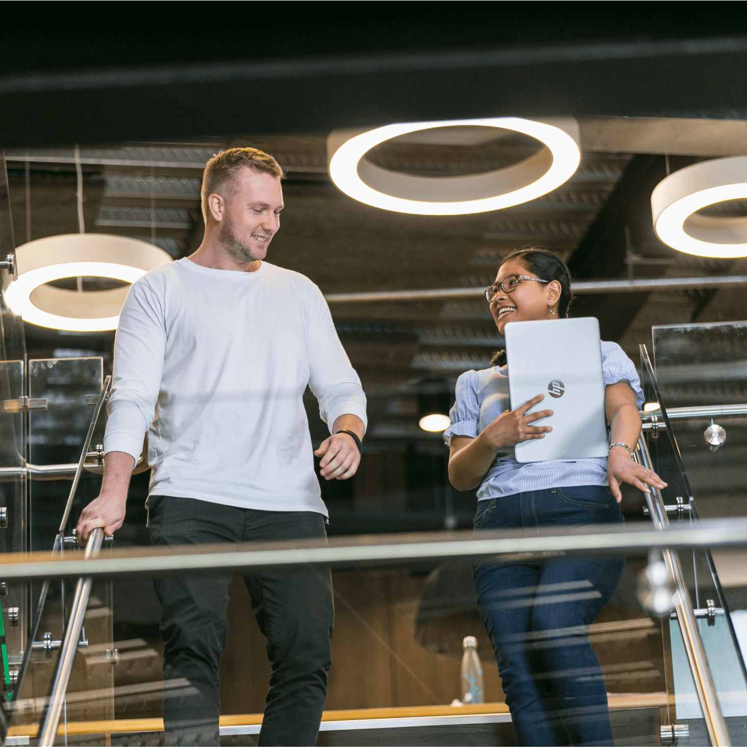 two Xero colleagues smiling and chatting whilst walking together to a meeting