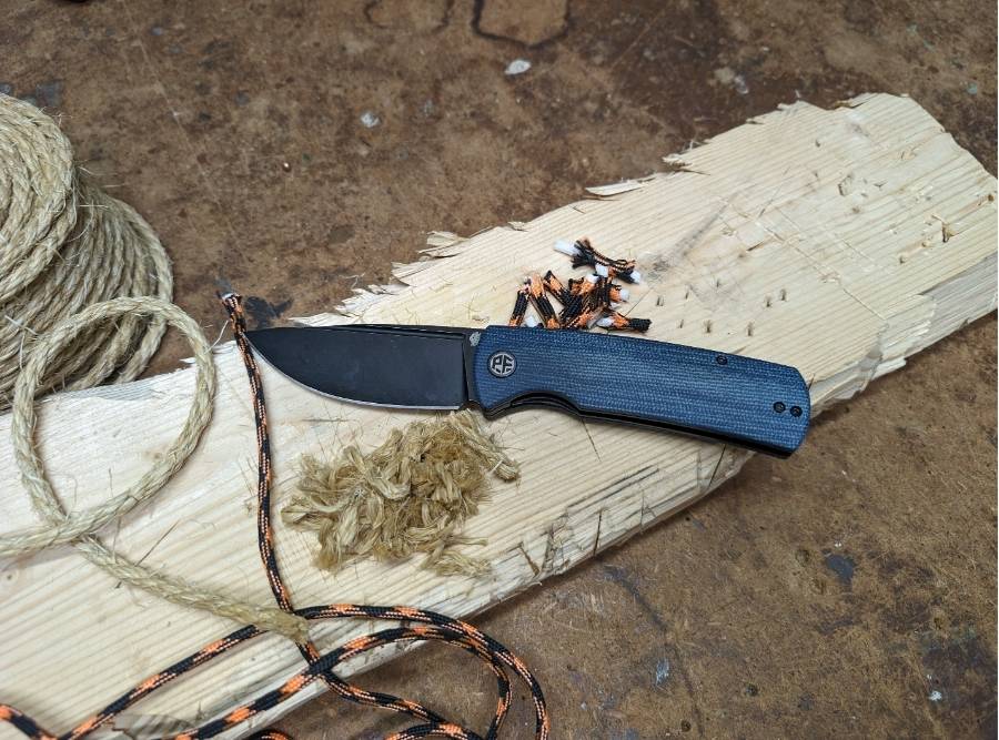 Petrified Fish Beluga PFP01 folding knife with blue handle cutting rope and paracord on wooden surface.